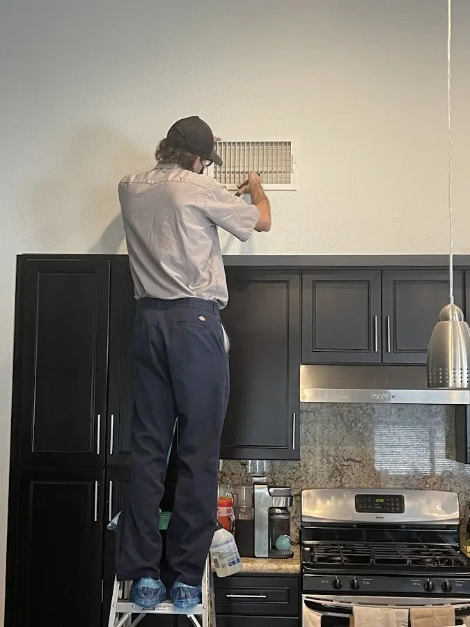 Technician inspecting an air vent during HVAC service in Gloucester